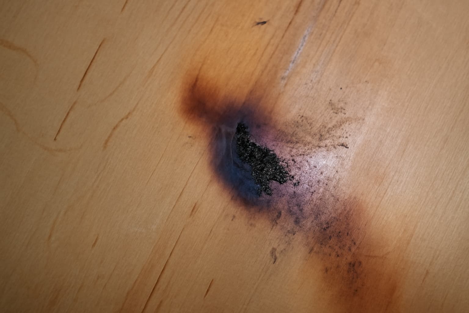 A burned wood surface with black spots.